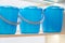 Three new plastic blue utility buckets with lid on the shelf. Industrial background with household goods