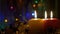 Three New Year`s candles and Christmas decorations. Blurred background with colored lights. Exit from the zone of not