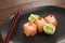 Three nigiri sushi served in black plate with chopsticks