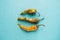 Three old dried and spoiled yellow peppers on blue background, top view