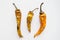 Three old dried and spoiled yellow peppers on white background, top view