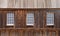 Three old glass windows in a wood wall, rustic wood roof.