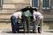 Three old men inspect the engine under the bonnet of a Morris Minor Classic Car