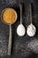 Three old spoons with brown, white and icing sugar on black background