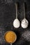 Three old spoons with brown, white and icing sugar on black background