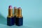 Three old used tubes of lipstick stand on a blue background.