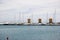 Three old windmills standing near blue Mediterranean sea