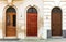 Three old wooden arched doors decorated with iron door knockers