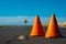 Three orange cones sitting on the side of road next to street sign. Generative AI