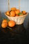 Three oranges beside wicker basket on black granite