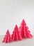 Three Origami Xmas trees, on grey table with off white background. Vertical photo image.