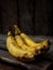 Three overripe bananas on a dark wooden background.