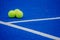 Three paddle tennis balls on a paddle tennis court