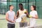 Three paddle tennis players talking on court