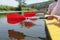 Three paddles are displayed in a row in the hands of the people floating in the kayak. The paddles are reflected in the calm water