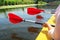 Three paddles are displayed in a row in the hands of the people floating in the kayak. The paddles are reflected in the calm water