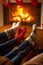Three pair of feet in socks warming at burning fireplace at house