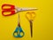 three pairs of colored scissors on a yellow background