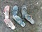 Three pairs of old slippers on the ground with dry grass and a little green grass.