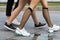 Three pairs of slim fit young girls legs in different sport shoes walking fast along the concrete road.Busy city lifestyle.