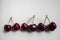 Three pairs of sweet red cherries arranged in a row on a white background. Food and drink concept