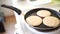 Three pancakes are fried in a frying pan, on an electric stove.