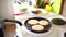 Three pancakes are fried in a frying pan, on an electric stove, against the background of the kitchen table.