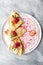 Three pancakes, sour cream and jam on a round plate on an old worn table