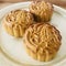 Three Pandan MoonCake in a round shape plate on wooden background.