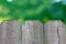 Three panels of wooden fence with blurry green trees bokeh in background