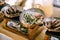 Three pans with Serbian cheapchichi sausages and vegetables on the stove on a blury background.