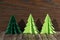 Three paper origami Christmas trees on a wooden background