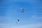 Three paragliders in a sunny blue sky