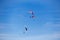 Three paragliders in a sunny blue sky