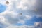 Three paratroopers jump with parachutes on the blue sky with white clouds background