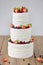 Three parts naked wedding cake with fruits and berries