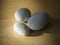 Three pebbles - white and grey on natural wood desk