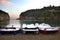 Three Pedal Boats with Folded Canopy Lining Up along the Shore. Two Cliffs Standing near the Beachfront. Coarse Sand and