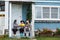 Three people in background of village house on farm talk and laugh.