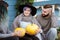 Three people in background of village house on farm talk and laugh.