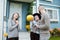 Three people in background of village house on farm talk and laugh.