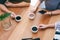 Three people holding coffee cups to drink on wooden table