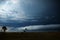 Three people look at the looming clouds over the sea during a storm