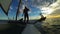 Three people sailing on windsurfing catamaran against twilight sky over ocean