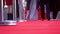 Three people are walking on the red carpet, low angle close up