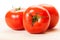 Three perfect red tomatoes on a wooden board