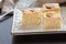 Three Pieces Basbousa Traditional Arabic Semolina Cake with Almond Nuts Orange Blossom Water. Selective Focus. Dark background