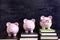 Three piggy banks with blackboard, college graduation or savings fund concept