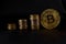 Three piles of coins in ascending order, and a Golden coin bitcoin on black leather