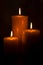 Three Pillar Candles Burning in a Dark Room